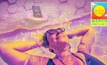 A woman relaxing in water while her smartphone sits apart, a sad face on its screen.