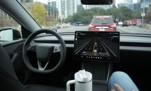 A safety monitor rides in the front passenger seat as a Tesla Robotaxi drives on South First Street in Austin on Wednesday, Jan. 21, 2026. 