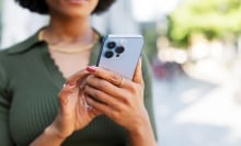 Woman holds cell phone in hand while she looks at it.
