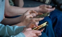 Three teenage boys look at their smartphone screens