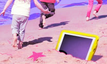 Kids leave a tablet in the sand as they have fun during the summer off screens.