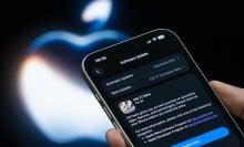 n iPhone displays the Apple iOS 27 Beta software update page in front of an illuminated Apple logo
