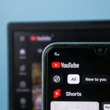 A laptop screen and a phone screen on the YouTube homepage.