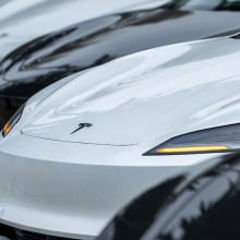 A row of Tesla vehicles in a parking lot.