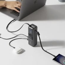 anker laptop charger on table with several devices plugged into it