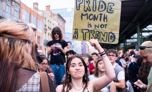 A person holds up a sign that reads "pride month is not a trend."