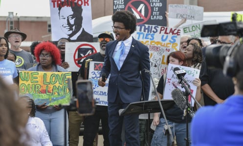 A group of protestors holding anti-xAI signs surround representative Justin Pearson. 