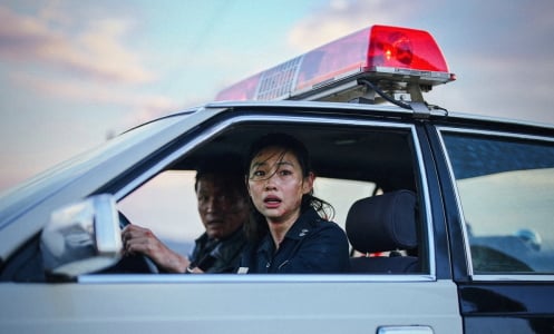 Two police officers look terrified in a police car in a still from the movie "Hope."