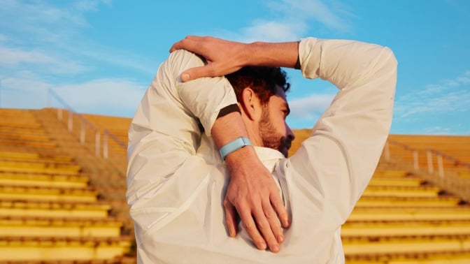 man stretching in stadium with google fitbit air on wrist