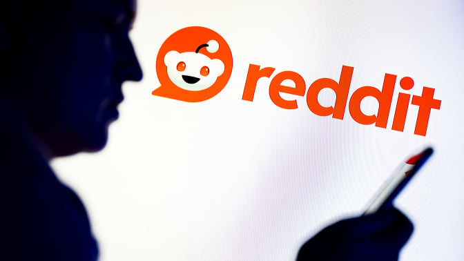 Reddit logo with smartphone user in the foreground